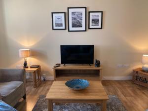 a living room with a tv and a coffee table at Pleacairn Cottage in Dalton
