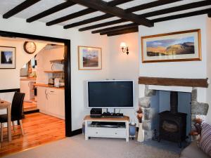a living room with a television and a fireplace at River View Cottage in Staveley