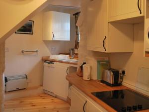 a small kitchen with white cabinets and a sink at River View Cottage in Staveley