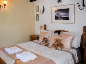 Dois ursos de peluche sentados em cima de uma cama em River View Cottage em Staveley