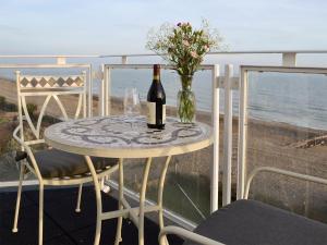 a table with a bottle of wine and flowers on a balcony at 5 Coast Lodge in Pevensey
