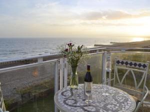 a table with a bottle of wine and a vase with flowers at 5 Coast Lodge in Pevensey