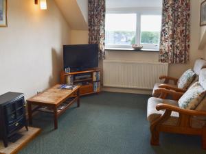 a living room with a tv and a couch and a table at Ffron Erch Cottages - 2712 in Llanarmon