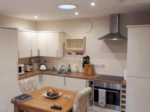 a kitchen with white cabinets and a wooden table at The Left Luggage Office in Falstone