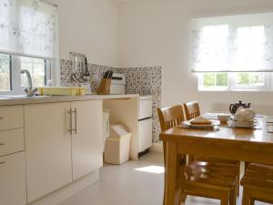 cocina con armarios blancos y mesa de madera en The Cottage - B4014, en Wendling