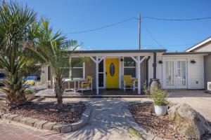 una casa con una puerta amarilla y palmeras en Cottage C, en Flagler Beach