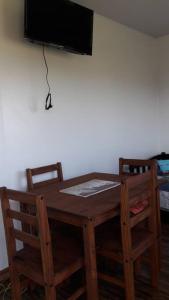 a wooden table with two chairs and a television on a wall at PUNTA NEGRA DISFRUTABLE TODO EL AÑO! in Punta Colorada