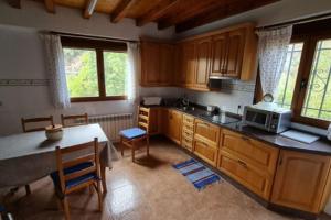 a kitchen with wooden cabinets and a table with a microwave at Casa da Pilar - A Ponte 