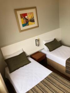Habitación con 2 camas y una foto en la pared. en Pampulha Lieu Hotel en Belo Horizonte