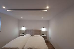 ミスワコビツェにあるVilla Fantastica Apartmentsの白い部屋の大型ベッド1台(2つの照明付)