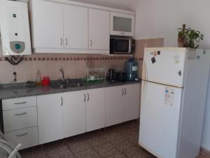 cocina con armarios blancos y nevera blanca en Santa Rita en Villa Carlos Paz