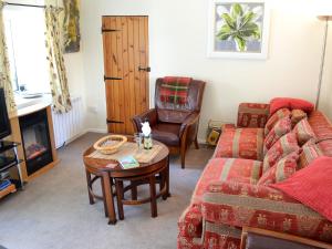 a living room with a couch and a table and a chair at Skyber Cottage in Lizard