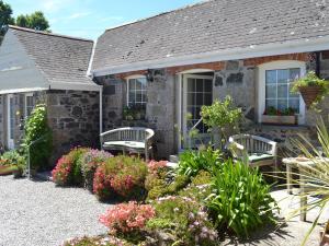 a stone house with two benches in a garden at Skyber Cottage in Lizard