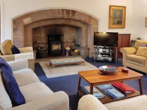 a living room with a fireplace and a tv at Whitehall Pele Tower in Mealsgate