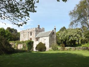 an old stone house with a green yard at Whitehall Pele Tower in Mealsgate