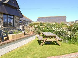 a wooden picnic table in the grass next to a house at The Old Stable in Holywell Bay