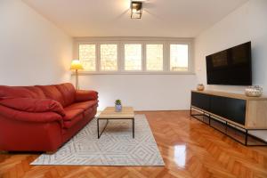 a living room with a red couch and a flat screen tv at MY DALMATIA - M Apartment Trogir with free parking and roof terrace in Trogir