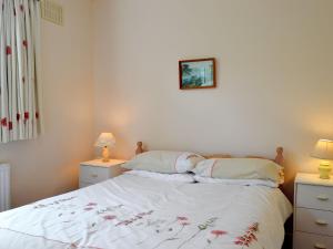 1 dormitorio con 1 cama con sábanas blancas y 2 lámparas en Whitegates, en Portinscale