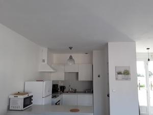 a white kitchen with white cabinets and appliances at Maison plain pied a 10 mn de la plage en campagne in Saint Malo