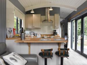 a kitchen with a counter and two bar stools at Ponsford Ponds Jacks Shepherd Hut - Bcponhut in Cullompton