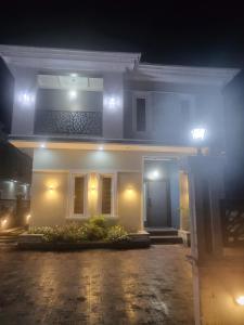 una casa bianca con una porta blu di notte di The Private Apartments: 2-Bedroom & 3-Bedroom a Port Harcourt