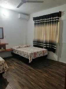 1 dormitorio con 1 cama y una ventana con cortinas en Casa shambieda en Santa Cruz - Huatulco