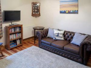 a living room with a brown leather couch and a tv at Jennys Cottage 27553 in Mundesley