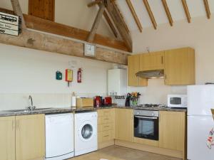 a kitchen with wooden cabinets and a washer and dryer at Kingfisher Cottage - 25114 in Flamborough