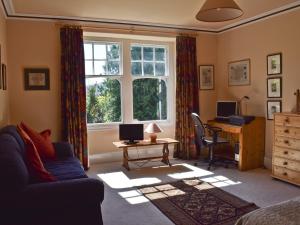 een woonkamer met een bank, een bureau en een raam bij Oakghyll in Windermere