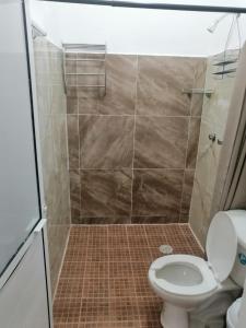 y baño con aseo y ducha de azulejos. en Casa shambieda en Santa Cruz - Huatulco