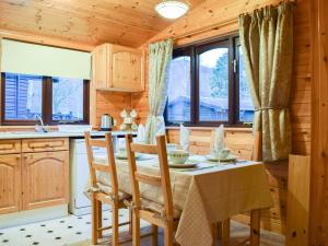 eine Küche mit einem Tisch, Stühlen und Fenstern in der Unterkunft Fern Lodge- Burnside Park in Keswick