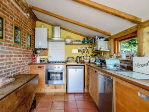 a kitchen with wooden cabinets and a brick wall at The Old Bike Shop in Brockdish