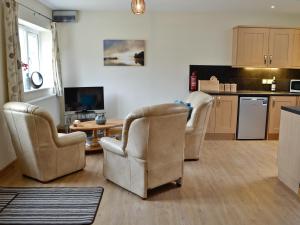 a living room with two chairs and a kitchen at Peach Tree Cottage in Winterborne Steepleton