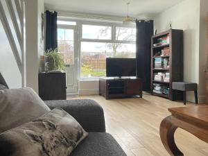 ein Wohnzimmer mit einem Sofa und einem Flachbild-TV in der Unterkunft The Cottage At Stanley Villa in Southport