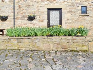 a stone wall with flowers in front of a building at The Stables - 24971 in Frosterley