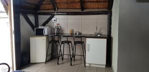 a kitchen with a counter with stools and a microwave at Oppihoek Gastehuis in Kroonstad