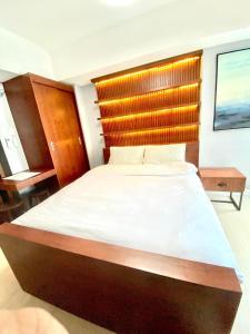 a bedroom with a large bed with a wooden headboard at Amirah’s Place Azure North in San Fernando