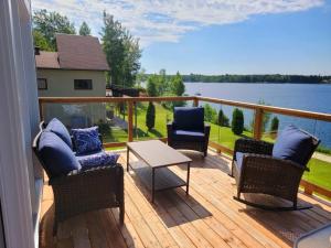 een balkon met stoelen en een tafel en uitzicht op het water bij Au paradis de l'Ashuap in Saint-Félicien