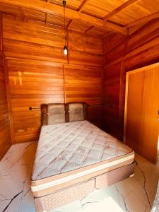 Cama pequeña en habitación con paredes de madera en Rest house en Laguna