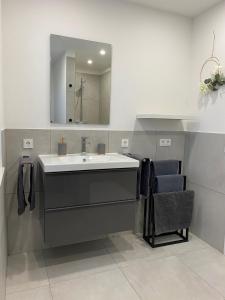 ein Badezimmer mit einem Waschbecken, einem Spiegel und einem Stuhl in der Unterkunft Moderne Wohnung in Heskem bei Marburg (Lahn) 