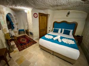 a bedroom with a bed with blue and white pillows at Milagre Cave Hotel in Göreme