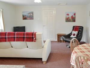a living room with a white couch and a chair at Foxglove Cottage in Wootton Fitzpaine