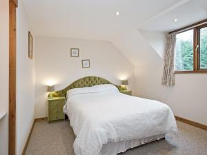a white bedroom with a bed and a window at Grebe Cottage in Dilham