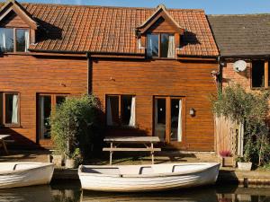 two boats are sitting in front of a house at Grebe Cottage in Dilham