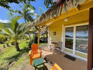une maison jaune avec des chaises et une table sur une terrasse couverte dans l'établissement Résidence COCO D'ILES, Gite TI BAMBOU, à Terre-de-Bas