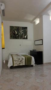 1 dormitorio con 1 cama y una pintura en la pared en Casas y departamentos, en Oxkutzcab