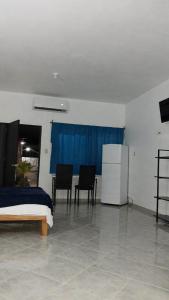 um quarto com uma cama, 2 cadeiras e um frigorífico em Casas y departamentos em Oxkutzcab