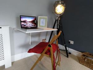 a laptop computer sitting on a desk with a lamp at Yellow Welsh Cottage-Coastal Retreat Village View in Bridgend