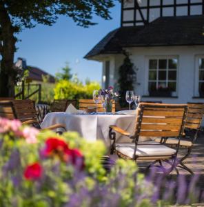 Hotel Waldhaus Föckinghausen في بيستفيغ: طاولة مع كؤوس النبيذ والزهور أمام المنزل