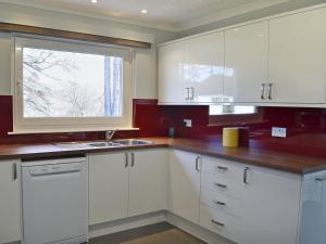 a kitchen with white cabinets and a window at Tall Pines in Carrbridge